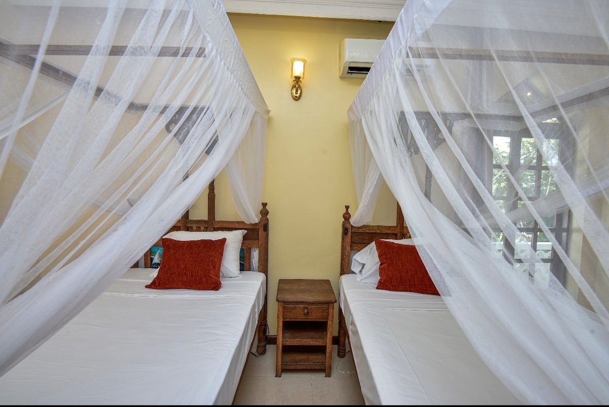 Double bedroom with arched garden door and lush greenery beyond